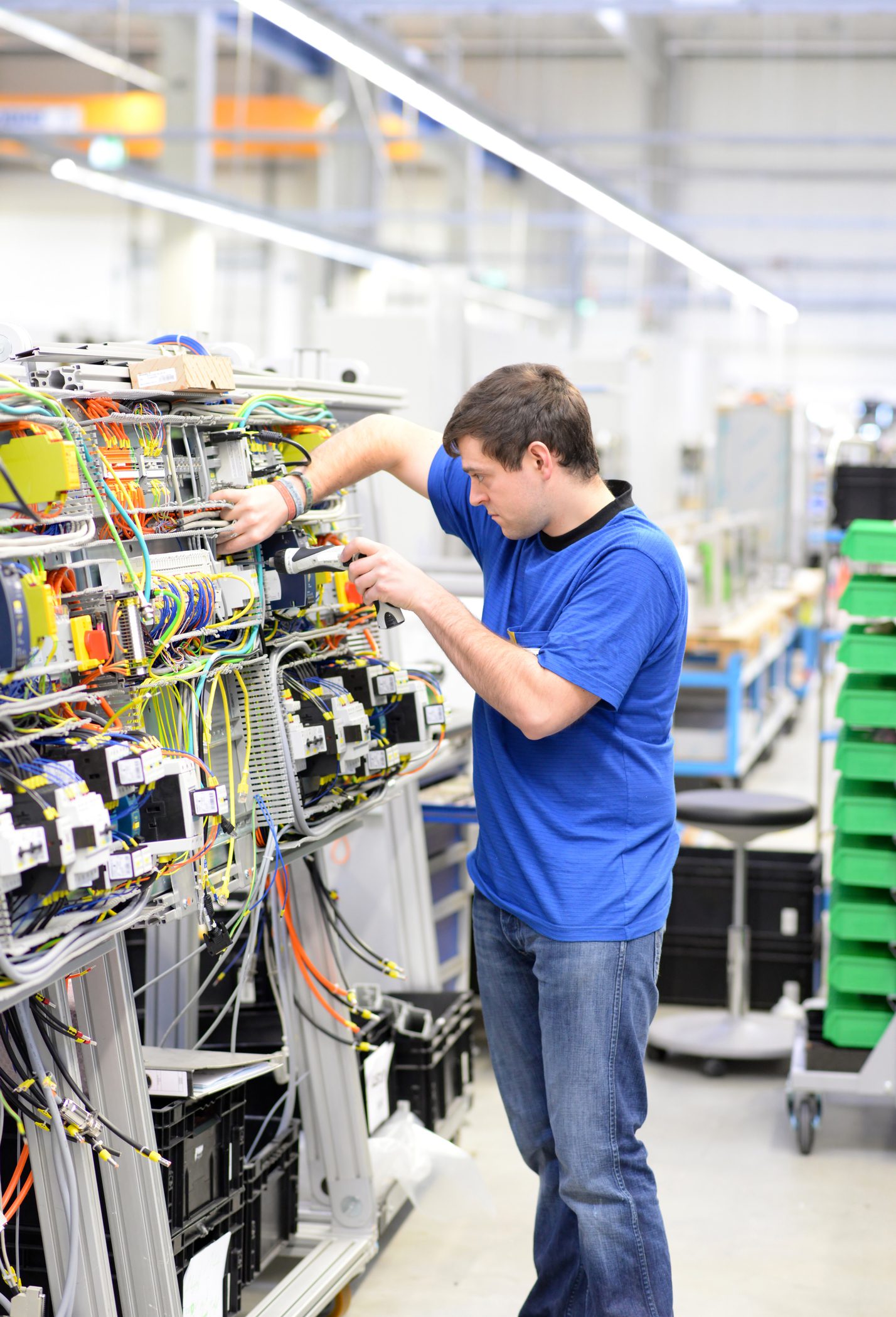 young apprentice worker in an industrial company assembling electronic components in the mechanical engineering of a modern factory