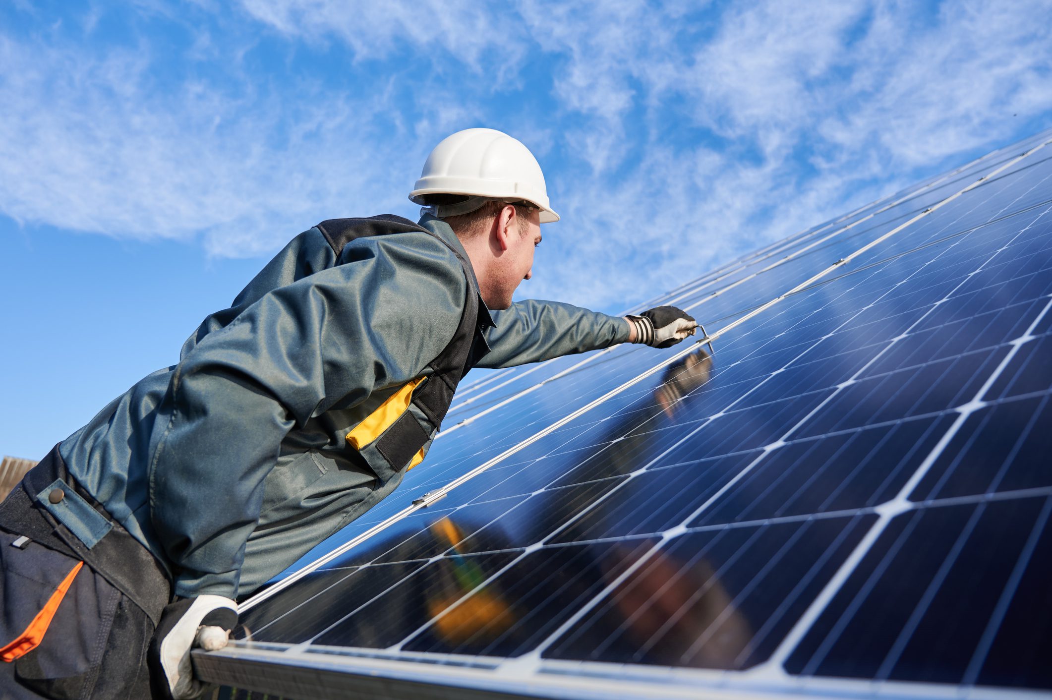 Workman standing on the ground trying to fasten solar batteries together, installing process