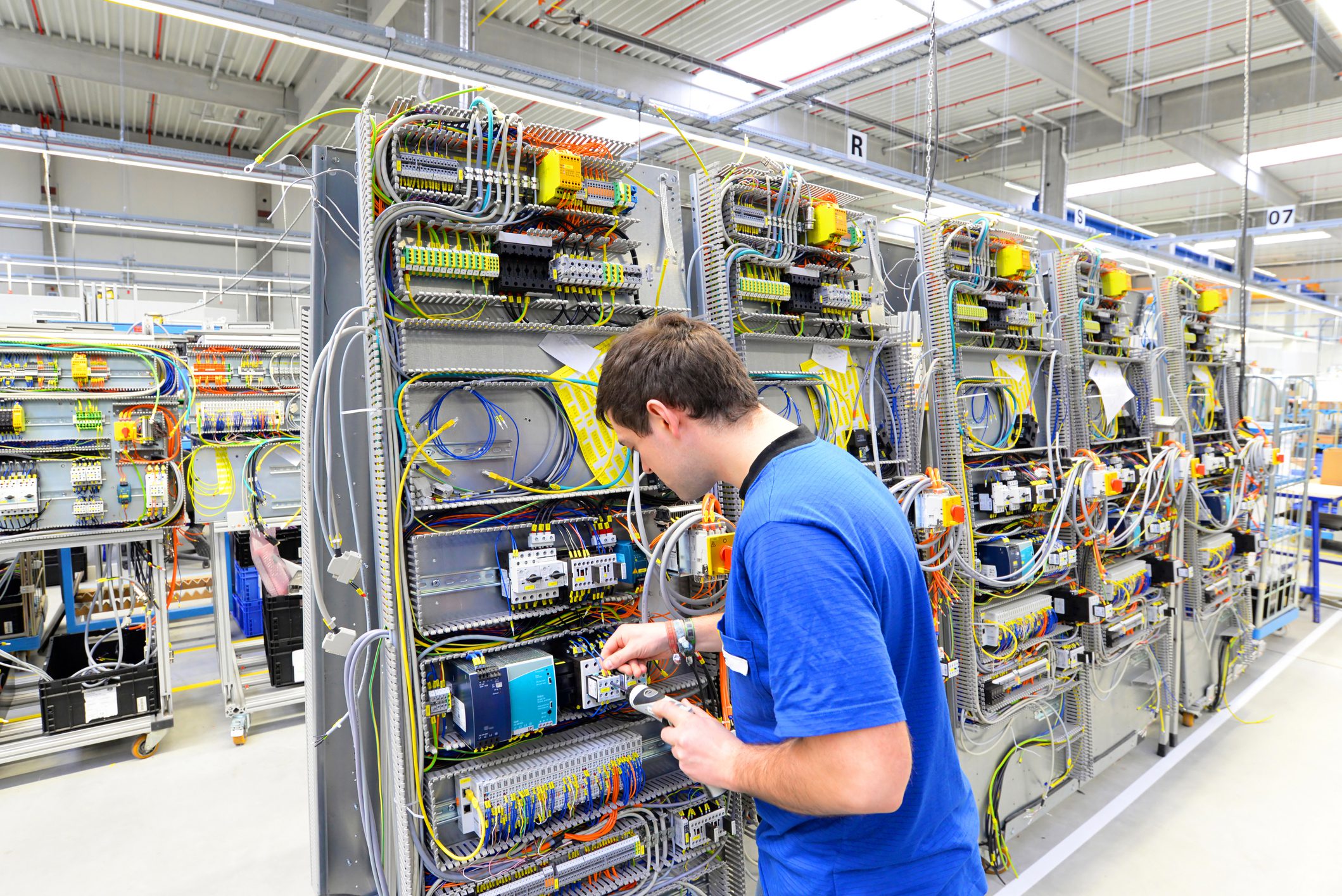 man assembles electronic components on a machine in a factory for mechanical engineering