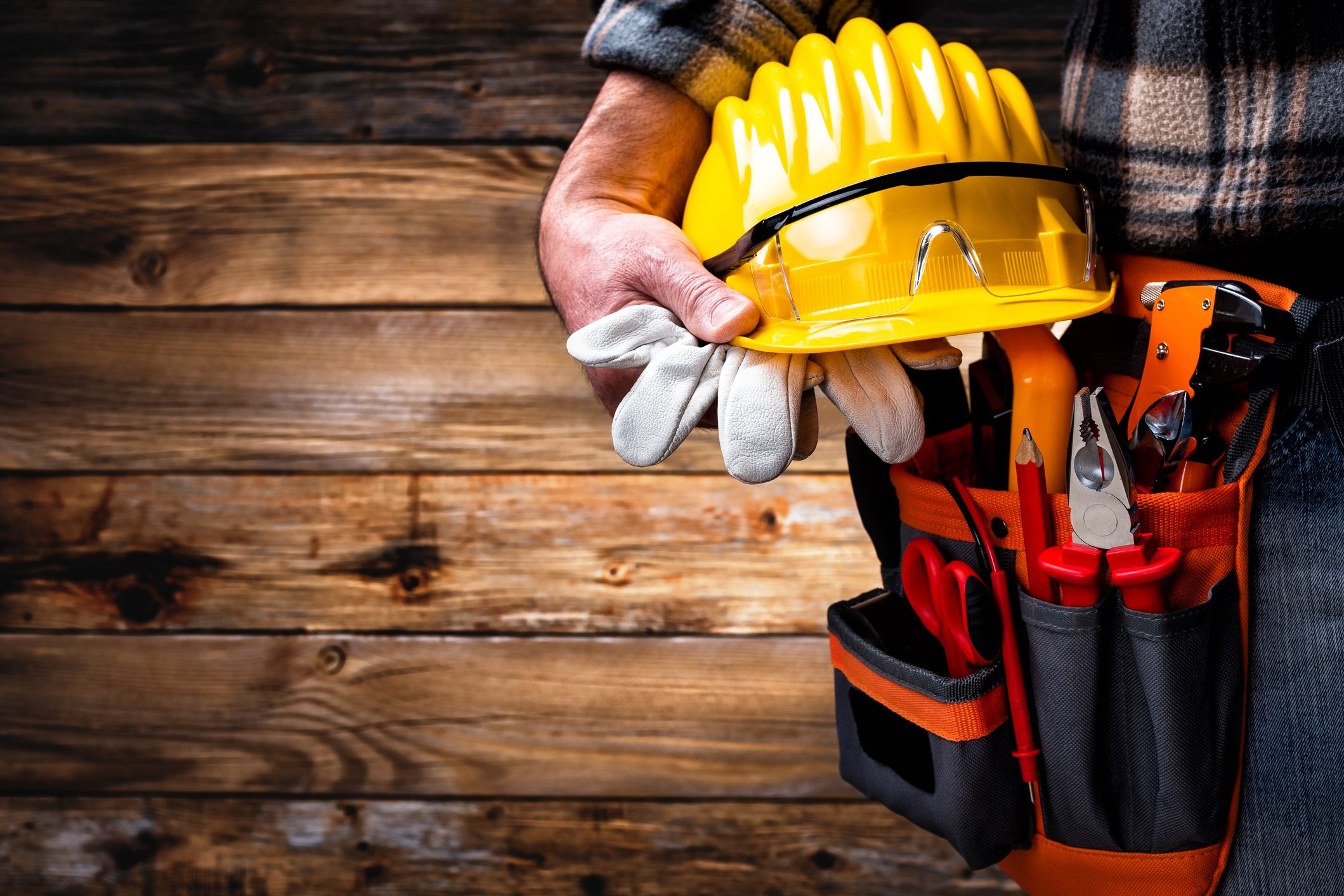 Electrician technician with tool belt on rustic wooden background