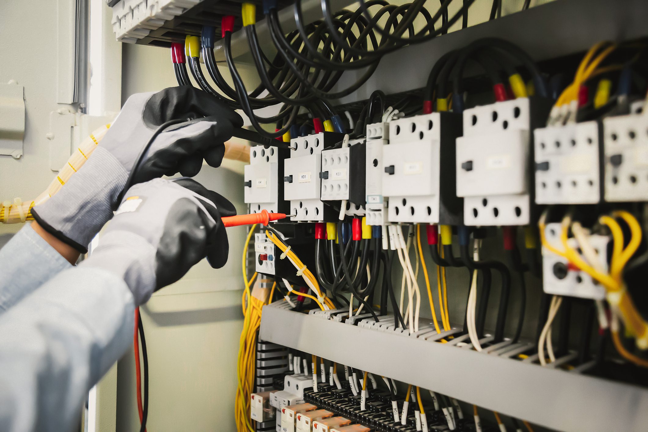 Electrical engineers test electrical installations and wiring on protective relays, measuring them with a multimeter.